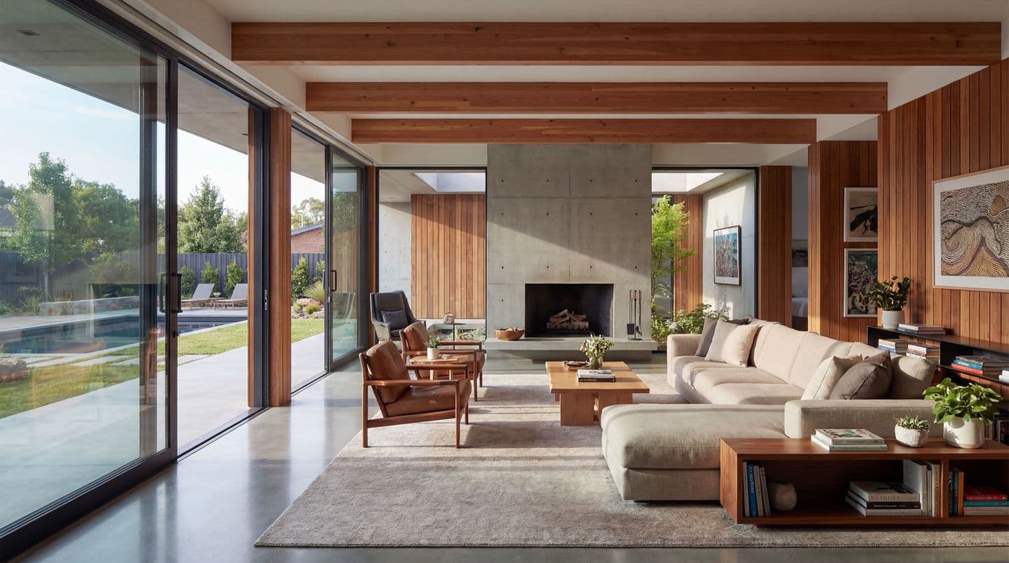 コンクリートの暖炉と木の梁があるモダンなリビングの内観パース。大きな掃き出し窓から庭のプールが見える、開放的な高級住宅のデザイン